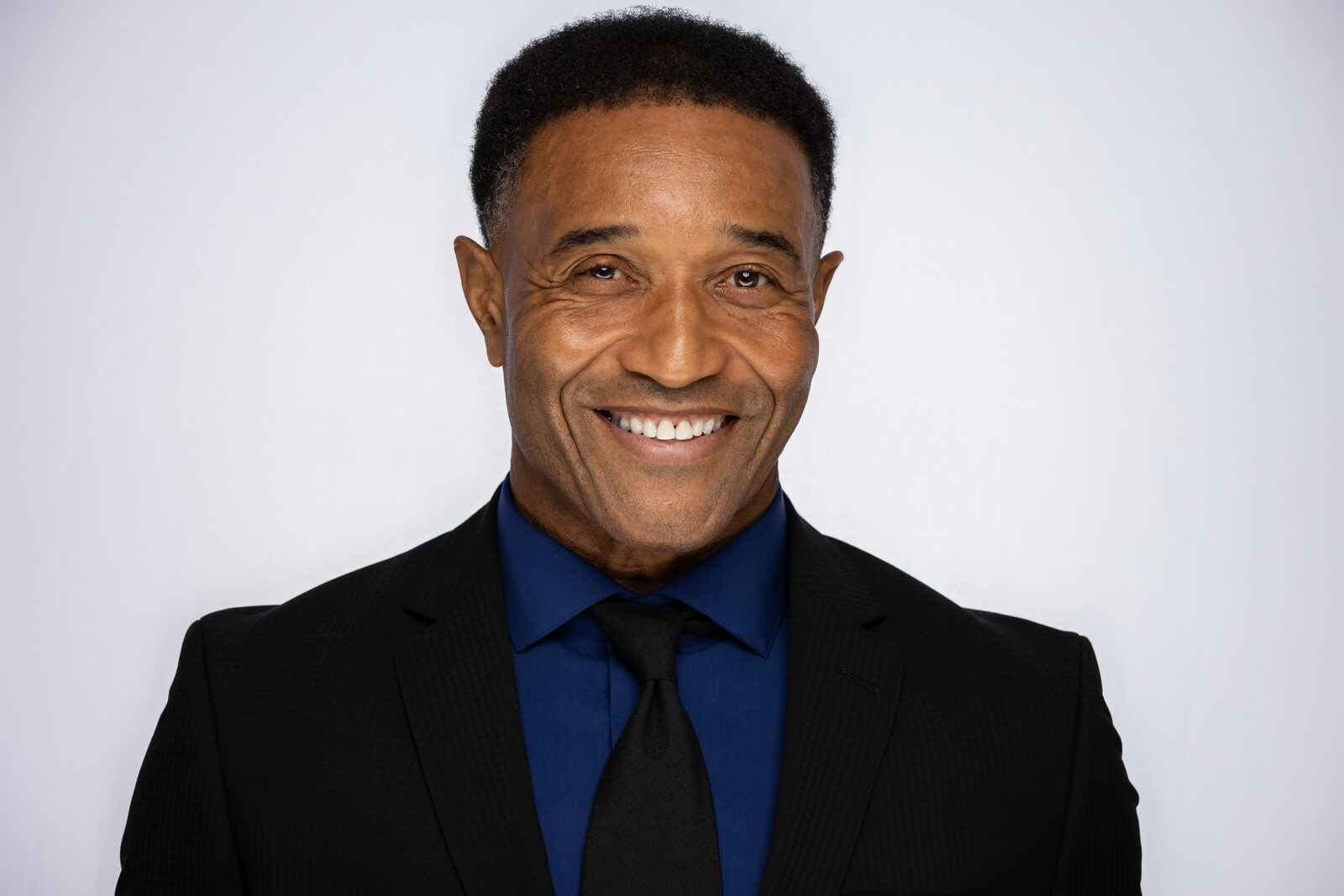 Actor headshot of Jeffrey in a dark suit, easy smile