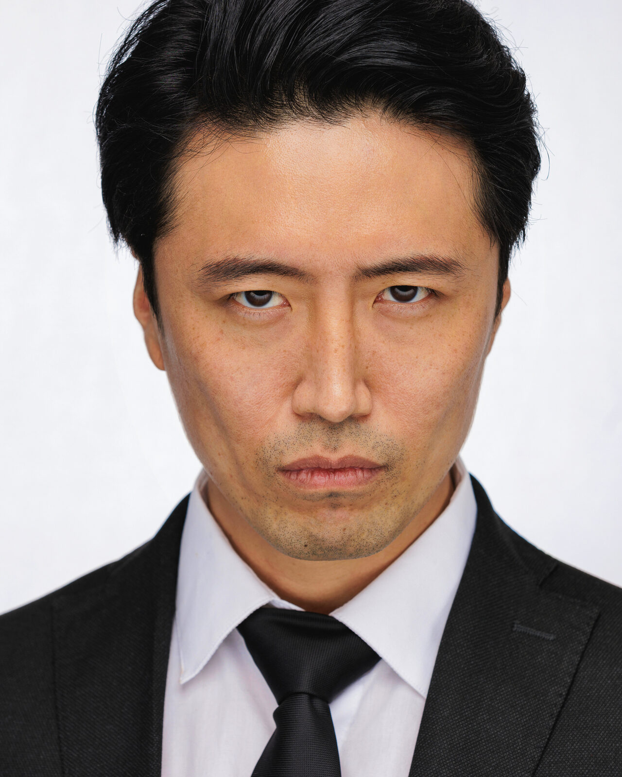 Finished headshot from that session, dark suit and tie, direct serious expression