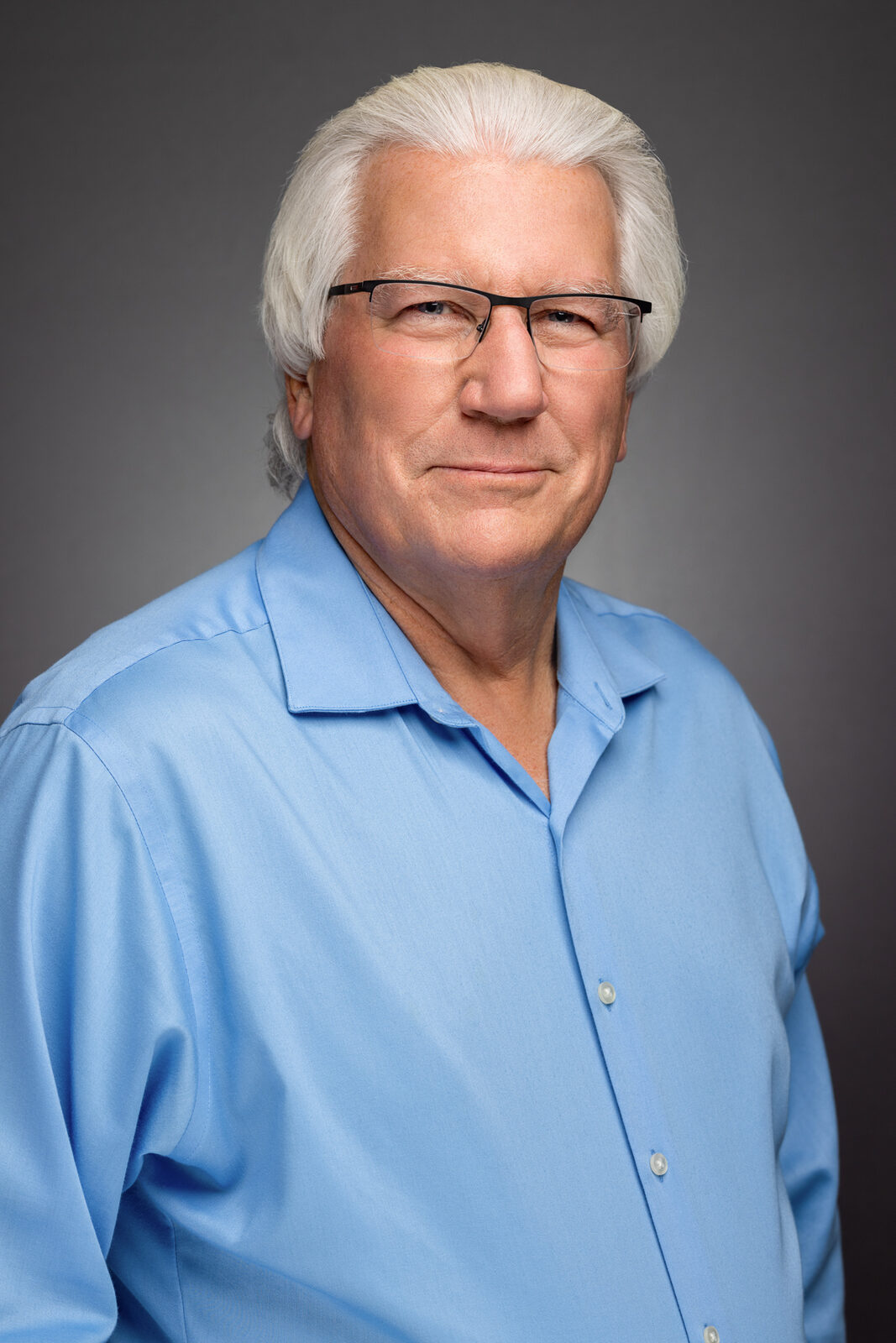 Corporate headshot of an executive in a blue shirt